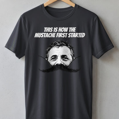 Dark gray t-shirt with white text "THIS IS HOW THE MUSTACHE FIRST STARTED" and a black and white graphic.