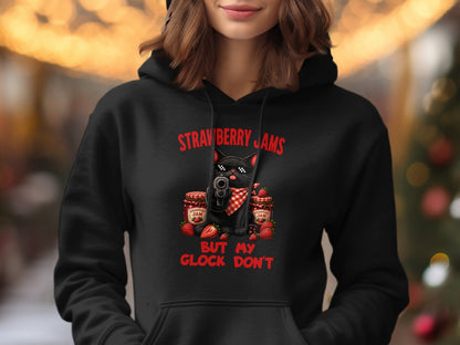 Black hoodie with a graphic of a black cat holding a gun and text reading "Strawberry Jams But My Glock Don't".