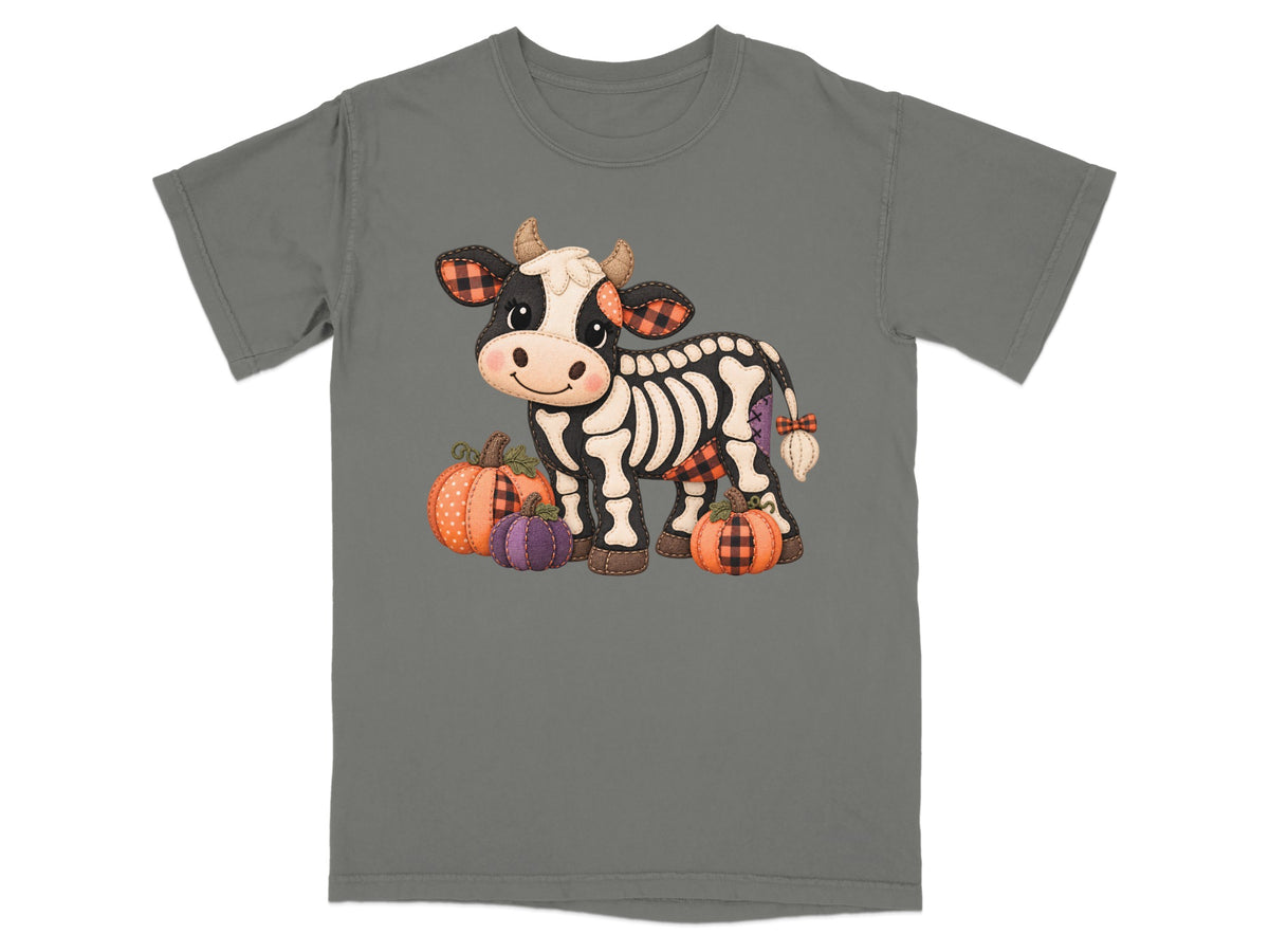 Skeleton cow with pumpkins wearing plaid accents, on a gray t-shirt.