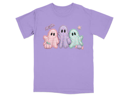 Three stitched Halloween ghosts in pastel colors with a bat, pumpkin, and candy on a purple t-shirt.
