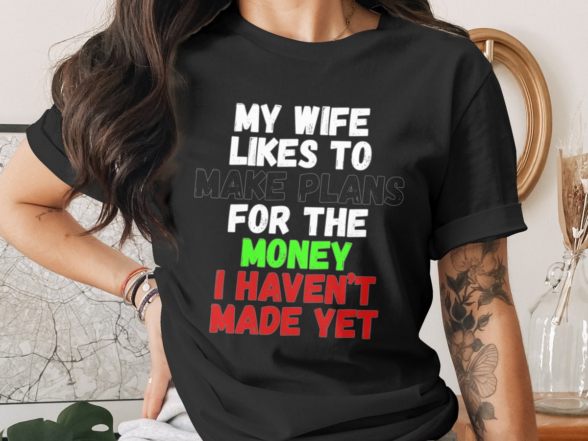 Black t-shirt with white text: "MY WIFE LIKES TO MAKE PLANS FOR THE MONEY I HAVEN'T MADE YET."