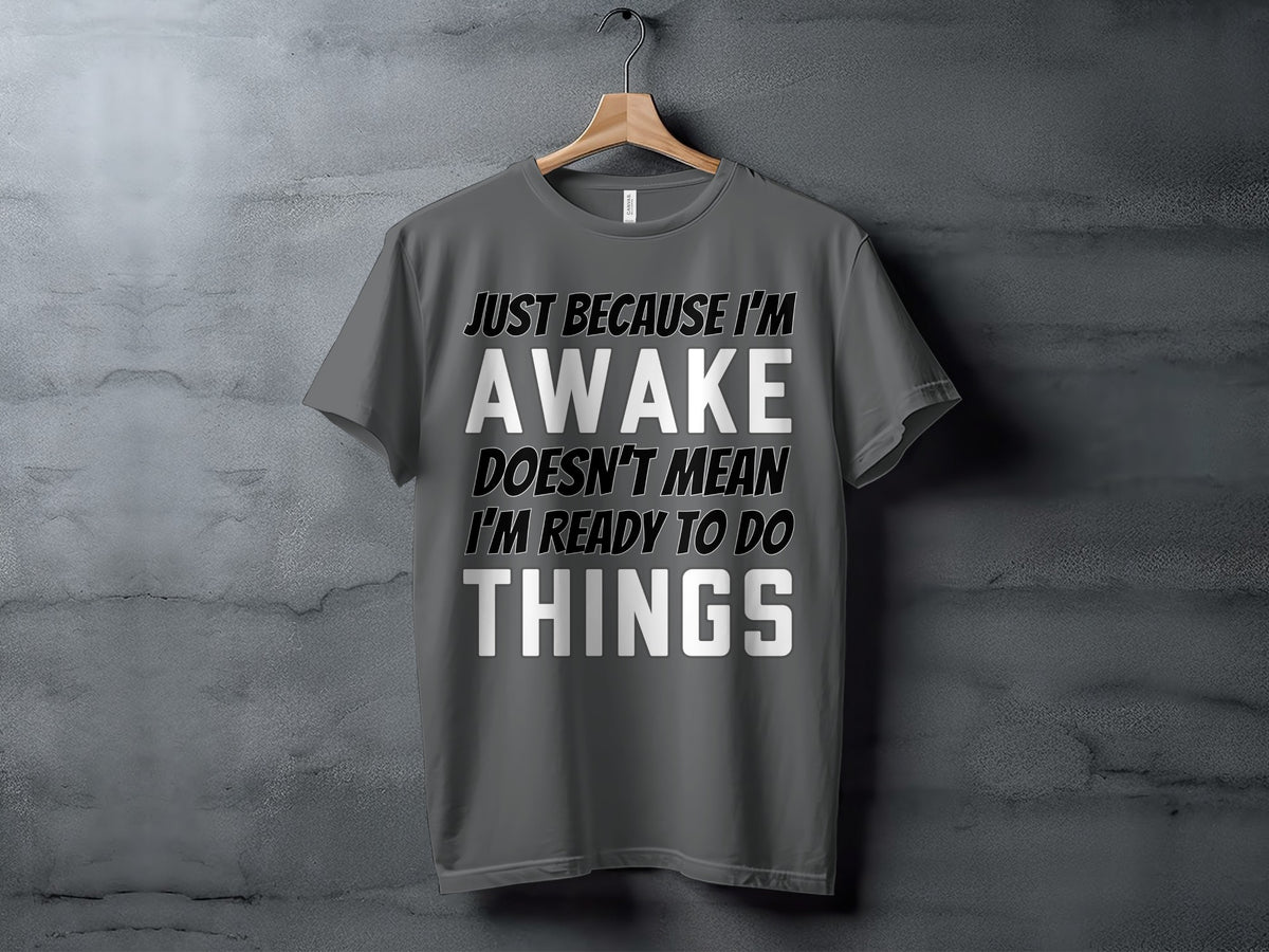 Gray t-shirt with text "JUST BECAUSE I'M AWAKE DOESN'T MEAN I'M READY TO DO THINGS".