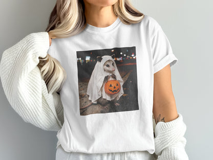 Opossum in a ghost costume holding a jack-o'-lantern trick-or-treat bucket.