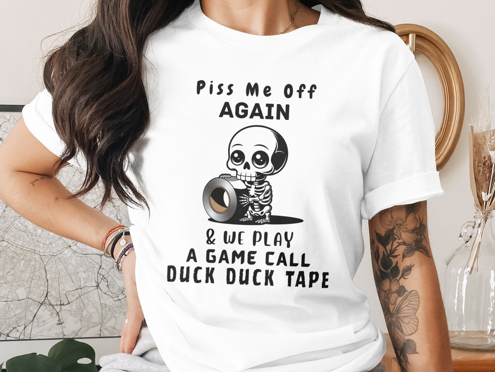 White t-shirt with cartoon skeleton holding duct tape, text reads "Piss Me Off Again & We Play A Game Call Duck Duck Tape".