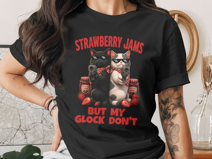 Black t-shirt with "Strawberry Jams But My Glock Don't" text and two cats with guns.