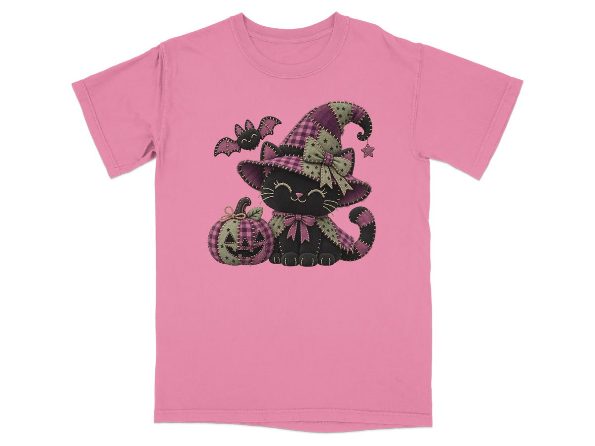 Pink t-shirt featuring a cartoon black cat wearing a witch hat beside a jack-o-lantern and a flying bat.