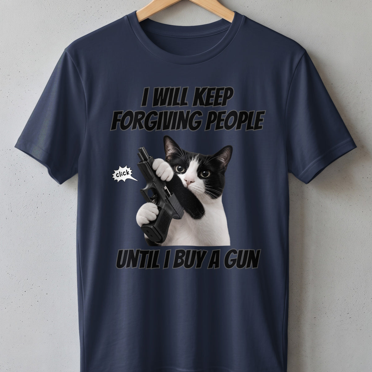 T-shirt with a black and white cat holding a gun and text "I WILL KEEP FORGIVING PEOPLE UNTIL I BUY A GUN."