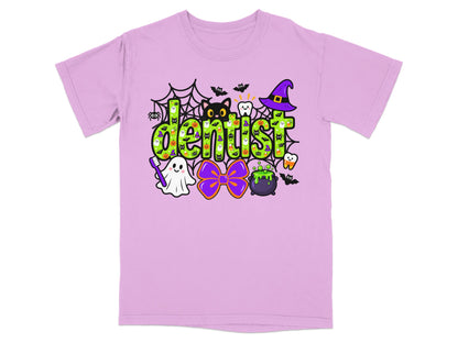 A light pink t-shirt with a green Halloween-themed graphic that reads "dentist" and includes various spooky icons.