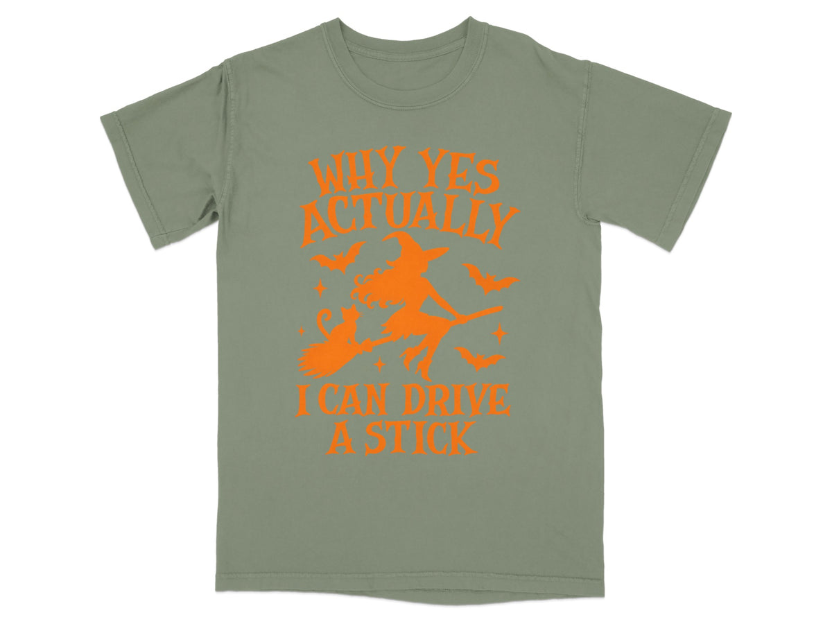 Olive green t-shirt with orange Halloween graphic and text reading "Why Yes Actually I Can Drive A Stick"