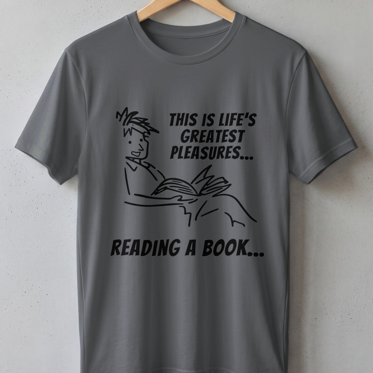 Gray t-shirt with line drawing of a person reading and text "THIS IS LIFE'S GREATEST PLEASURES... READING A BOOK...".