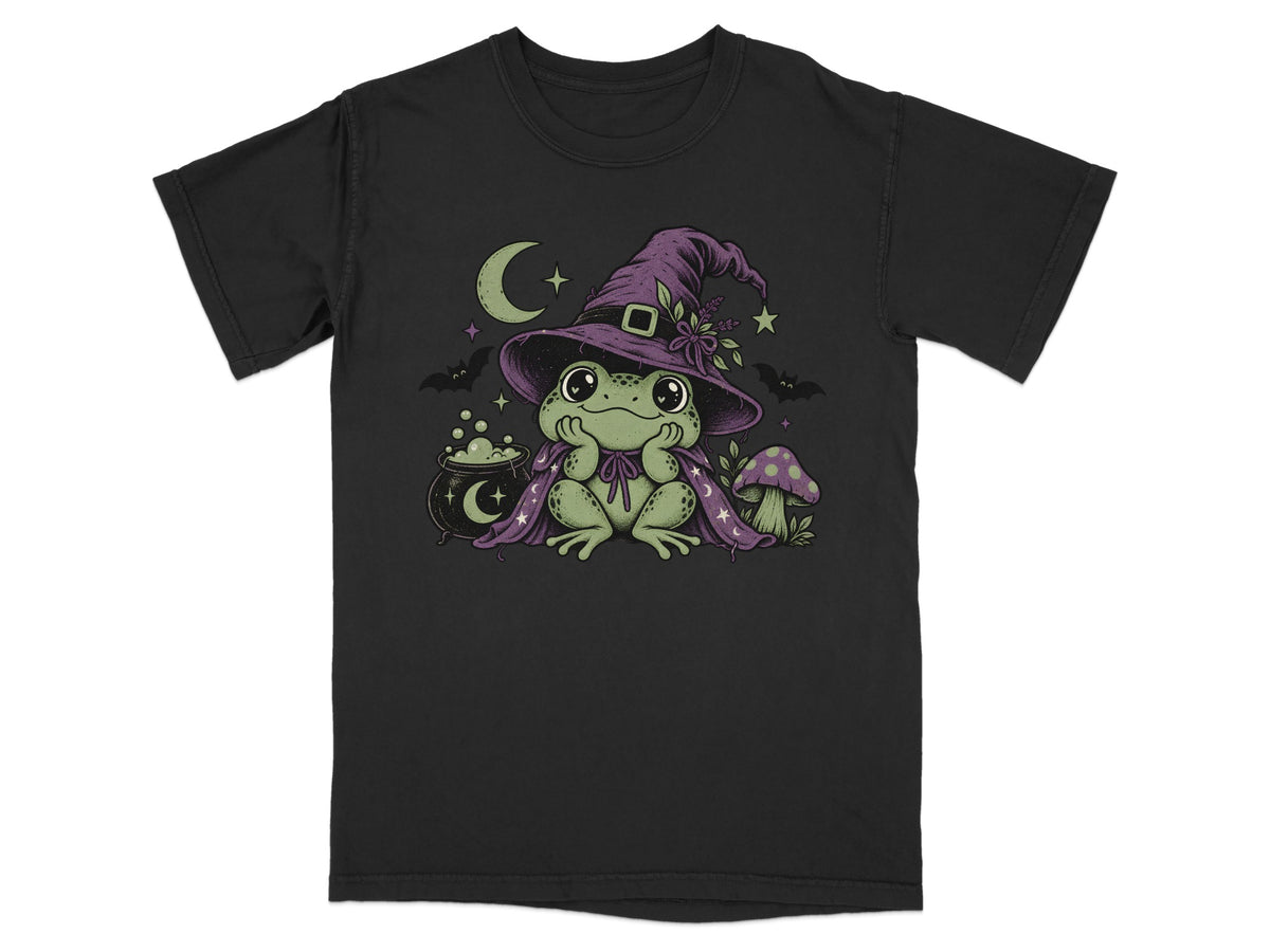 A black crew-neck t-shirt featuring a graphic of a cute green frog wearing a witch hat and cape.