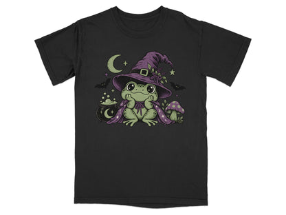 A black crew-neck t-shirt featuring a graphic of a cute green frog wearing a witch hat and cape.