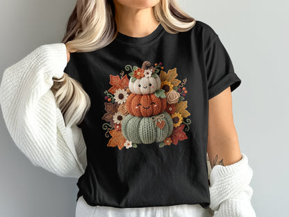 Black t-shirt with a knitted pumpkin stack surrounded by fall leaves and flowers.